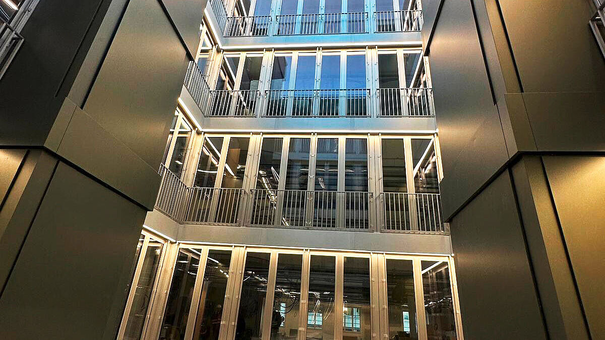 Die Innenhoffassade mit Satteldach. Markant sind auch die olivgrünen Blechverkleidungen der beiden Entrauchungsschächte. Bild Surber Metallbau AG