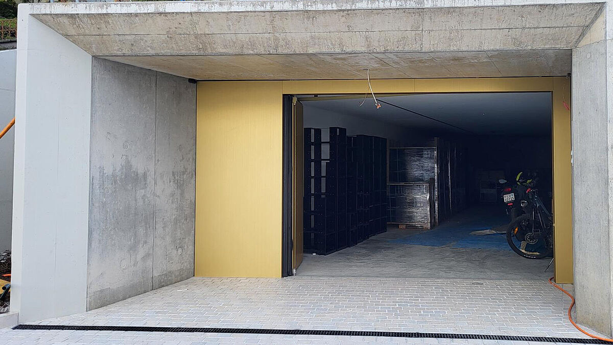 Garageneinfahrt mit automatisiertem Falttor. Die äussere Blechverkleidung wurde im Werk des Torbauers aufgesetzt.