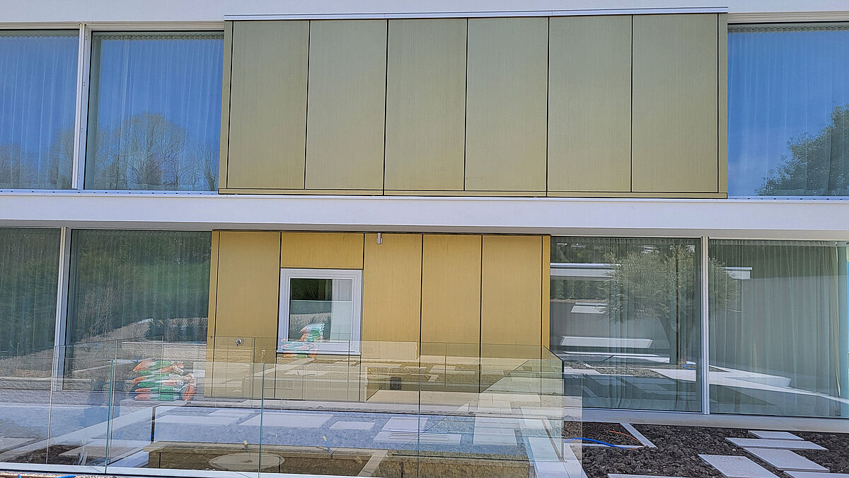 Gebäude-Bergseite: Während die seitlichen Gebäudeflanken transparent, mit hohem Glasanteil ausgebildet sind, ist die Aussenhaut im Bereich des Gebäudekerns als hinterlüftete Blechfassade ausgeführt.