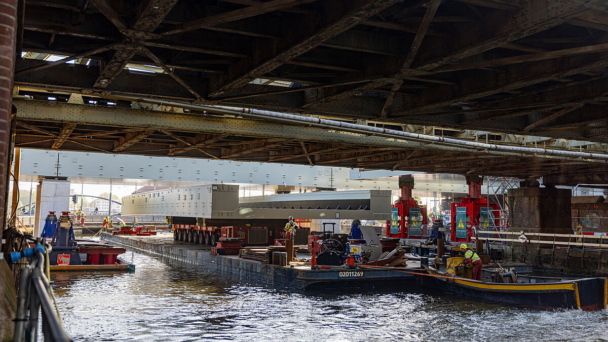 Das dritte Brückenteil wird unter der bestehenden Brücke durch, an seinen Zielort gebracht.