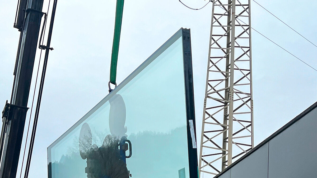 Le nouveau vitrage Oraé de Saint-Gobain Glass est transporté par grue jusqu’au lieu d’installation et intégré dans la nouvelle structure montants-traverses.