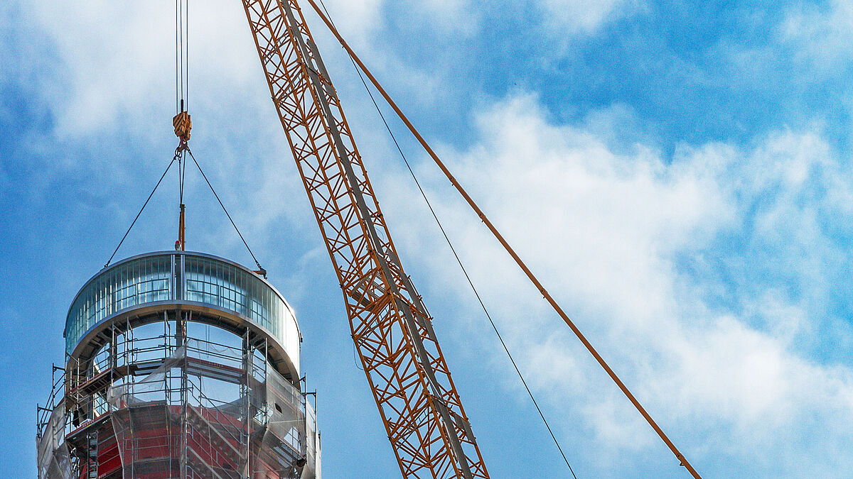 La couronne de la cheminée est abaissée lentement. Les supports HEB verticaux s’imbriquent dans la cheminée et stabilisent l’ensemble.