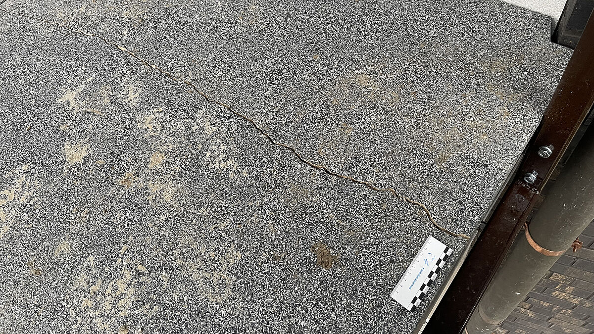 Balkonbodenplatte nicht nach Vorgabe des Herstellers montiert. Ein zu geringer Abstand an den Baukörper erschwert die Abdichtung und führte offensichtlich zu Rissen.