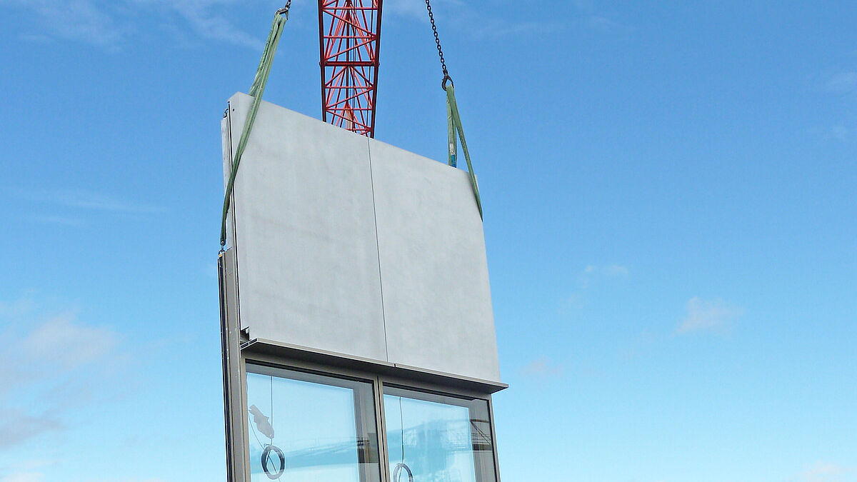 Photo : rédaction Montage des éléments de façade. Entreposés sur le toit, les éléments déjà vitrés et munis de béton renforcé de fibres de verre sont hissés à leur emplacement final.