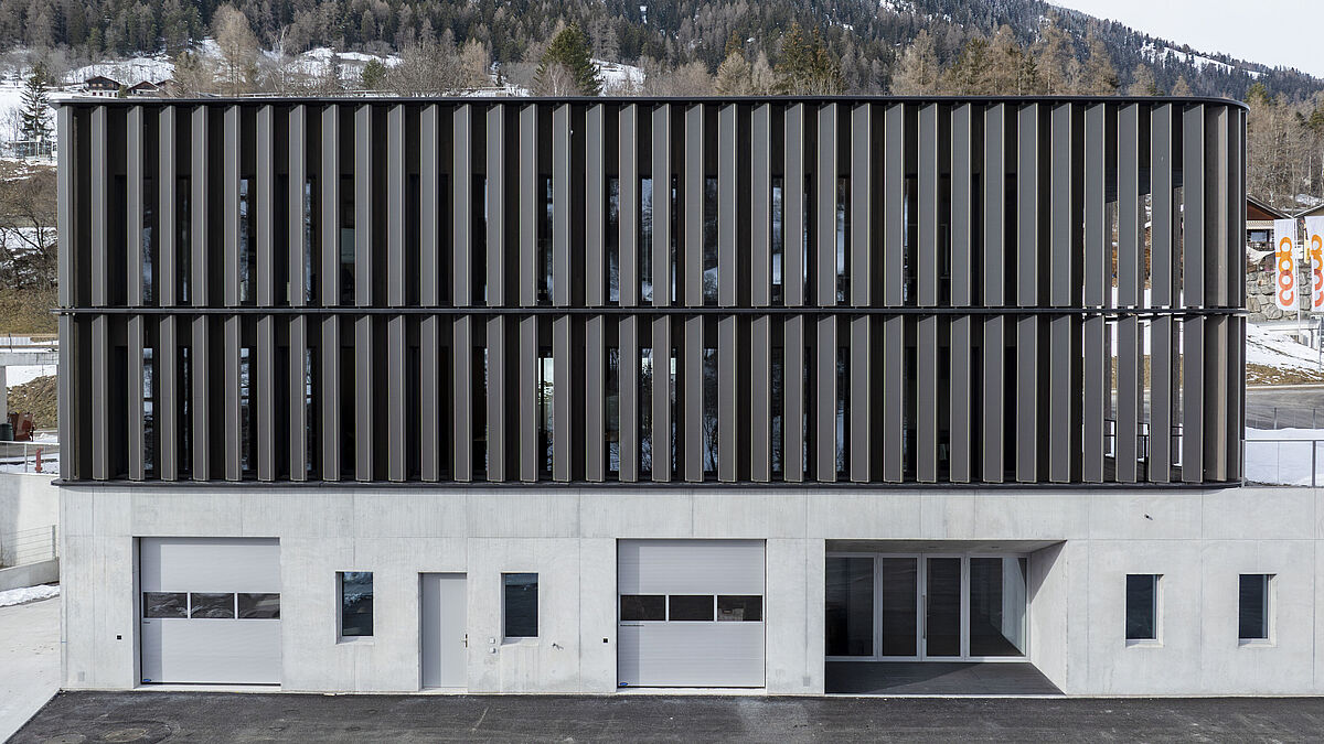 Frontansicht: Die vertikalen Lamellen erstecken sich über zwei Obergeschosse. Horizontal drei prägende Lisenenprofile.