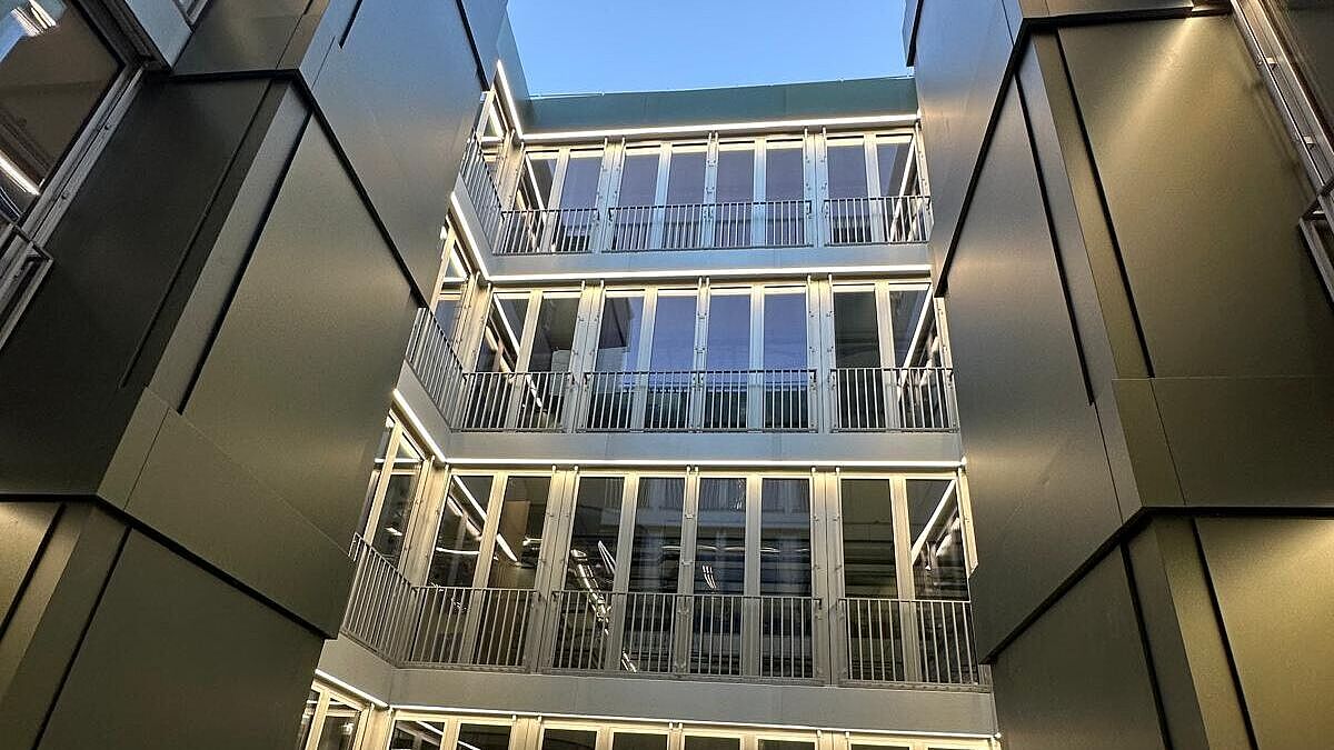 Die Innenhoffassade mit Satteldach. Markant sind auch die olivgrünen Blechverkleidungen der beiden Entrauchungsschächte. Bild Surber Metallbau AG 