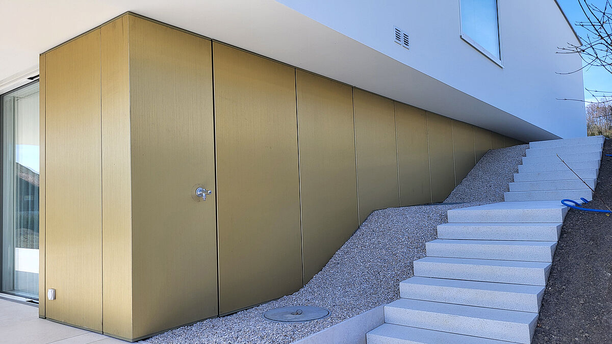 Hinterlüftete Blechfassade beim seitlichen Treppenaufgang. Gut zu sehen ist der tiefe, vertikale Schliff in den Blechen.