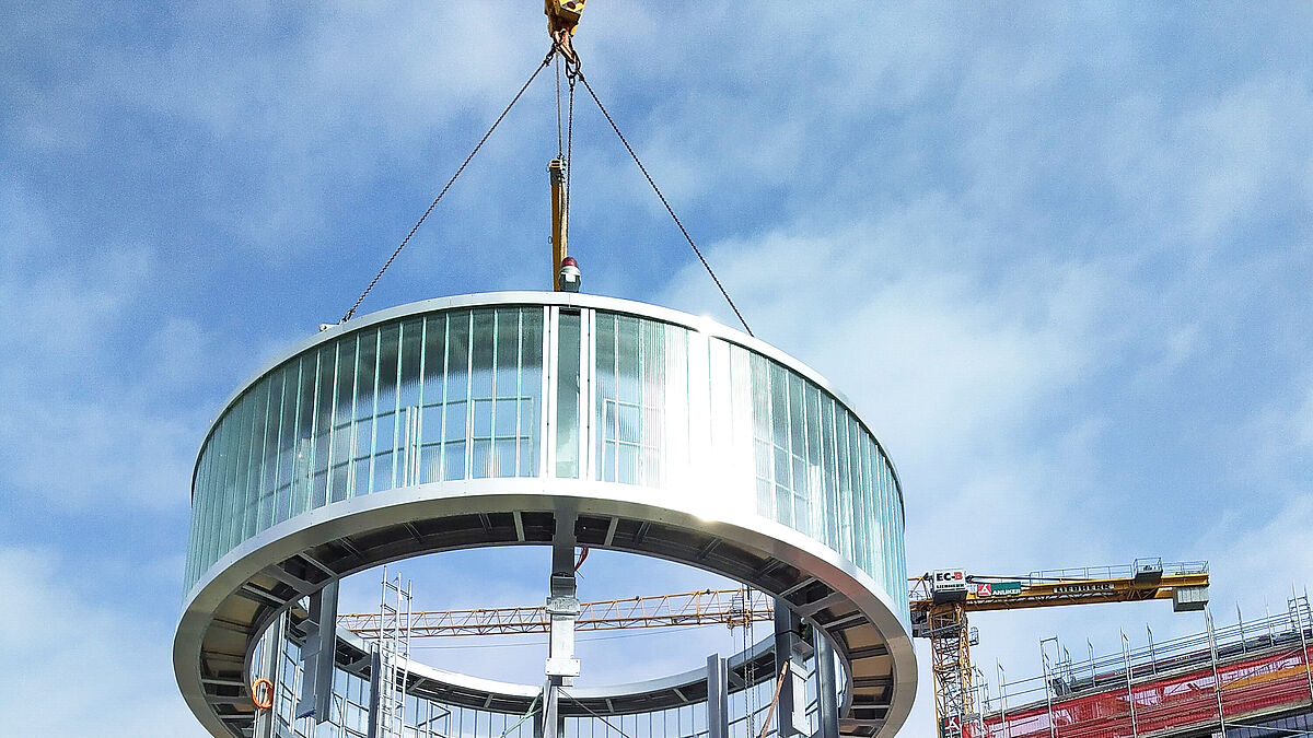 14 Tonnen an einem Lasthaken. Der zylinderförmige Kaminkranz wurde vor Ort am Boden komplett zusammengebaut. 
