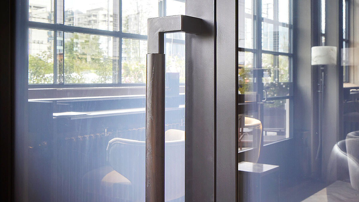 Massiver Stossgriff an filigraner Stahltüre Forster Unico. Auch der Griff scheint die Geschichte der Industrialisierung zu reflektieren.