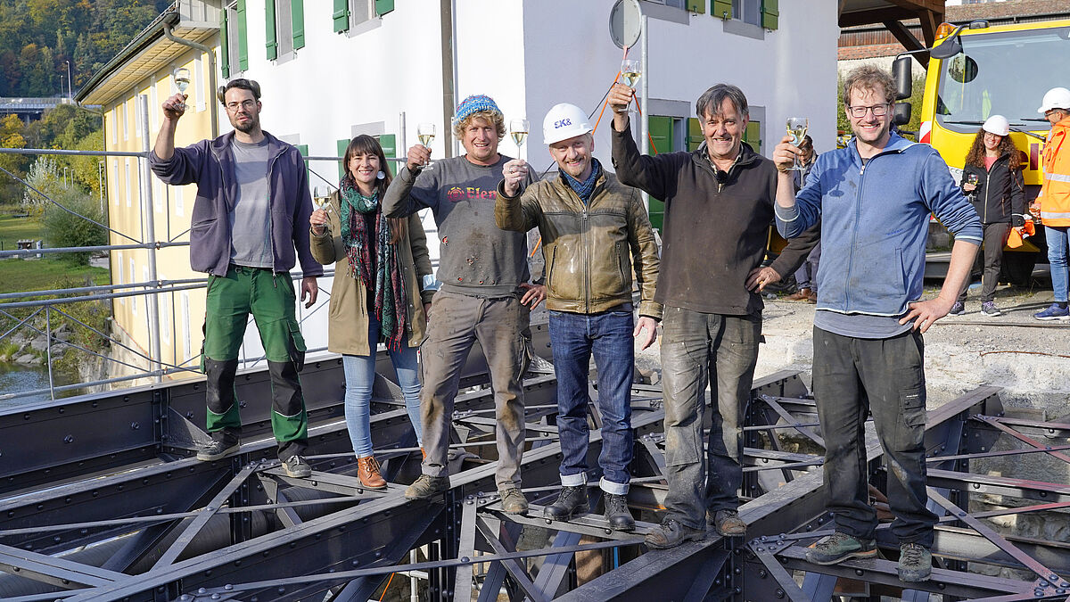 Die Beteiligten stossen auf das bestens gelungene Projekt an. Zweiter von rechts: Moritz Häberling. Die provisorische Unterbrücke schützt vor Absturz.
