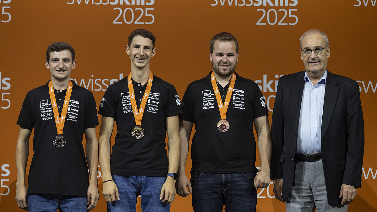 Siegerpodest: Die drei strahlenden erstplatzierten Metallbauer mit Bundesrat Guy Parmelin.