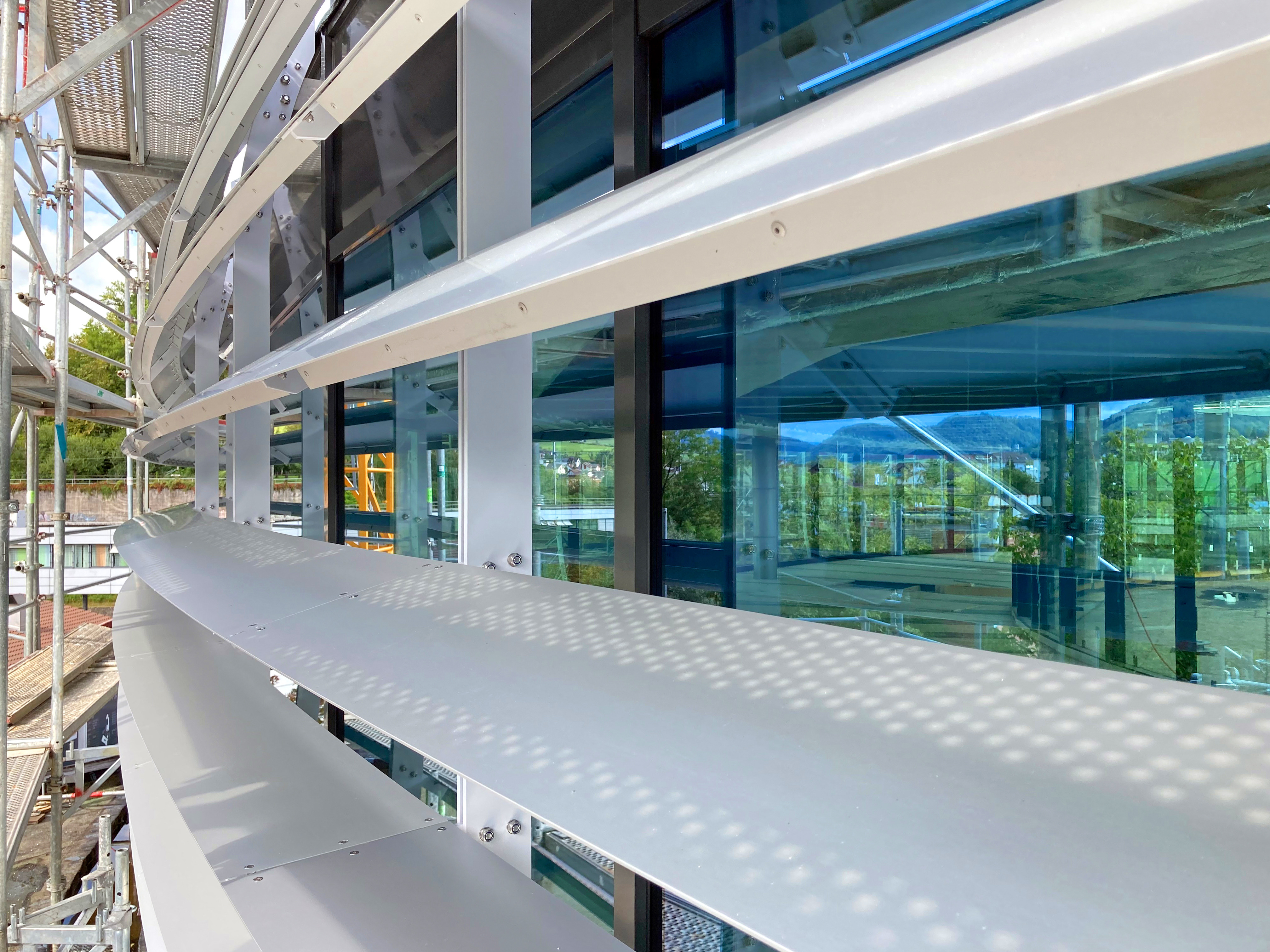 Aussenansicht während der Bauphase: Die Lamellen bestehen aus eloxiertem Aluminiumblech und sind unter Spannung an die örtlichen Konsolen befestigt.  Bild: Bäumlin+John AG